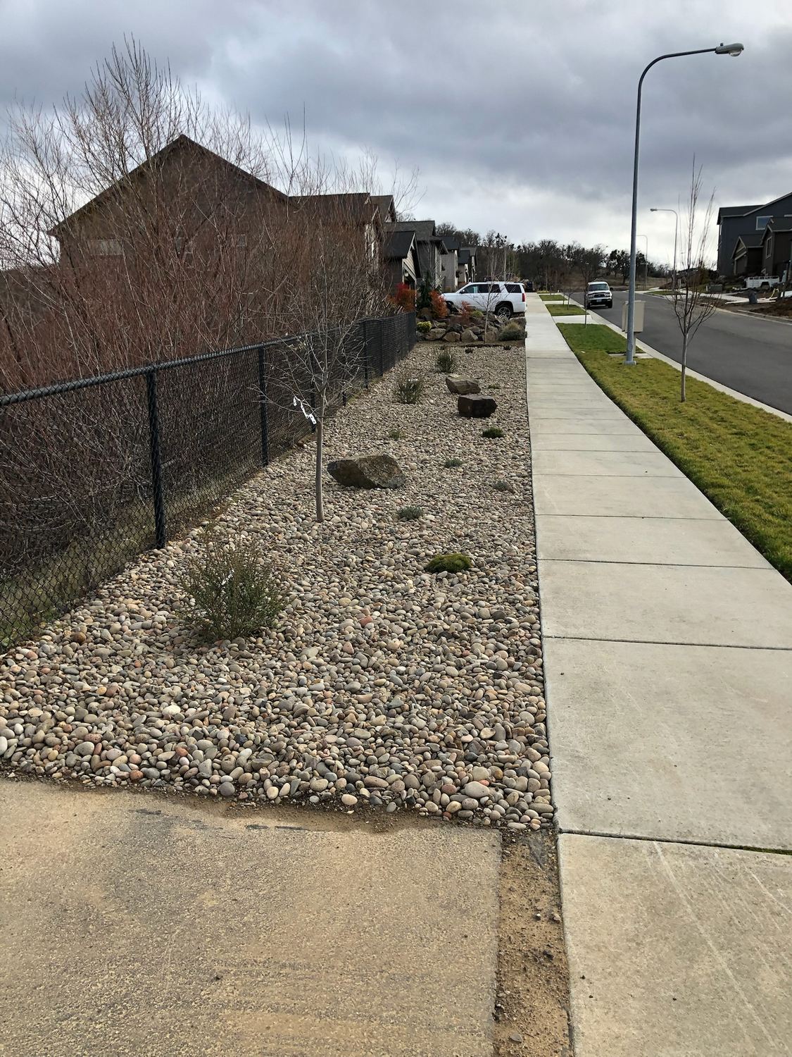 Rock-lined drainage area beside a sidewalk