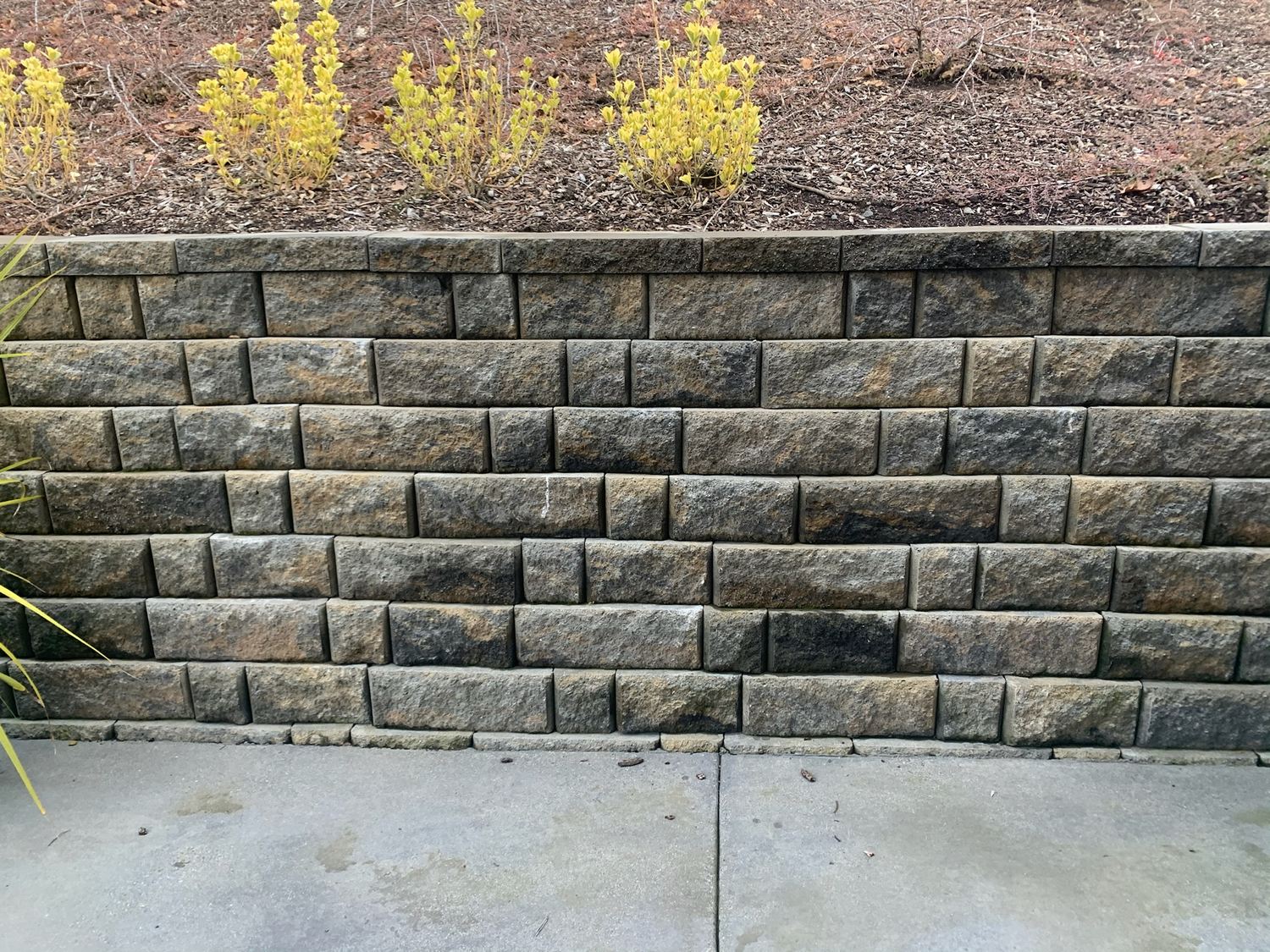 Straight block retaining wall beside a walkway