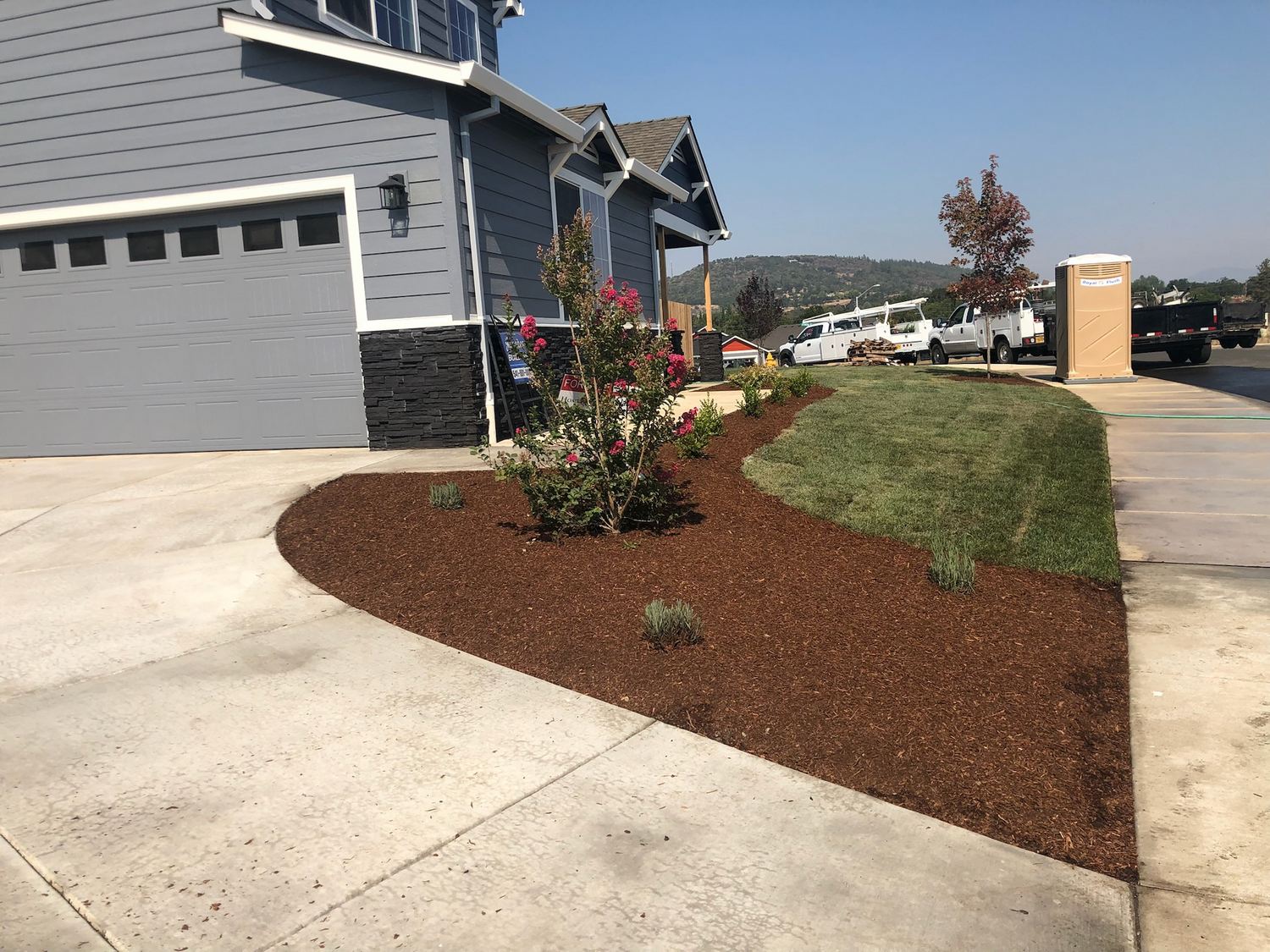 Prepared residential landscape site beside a home and driveway