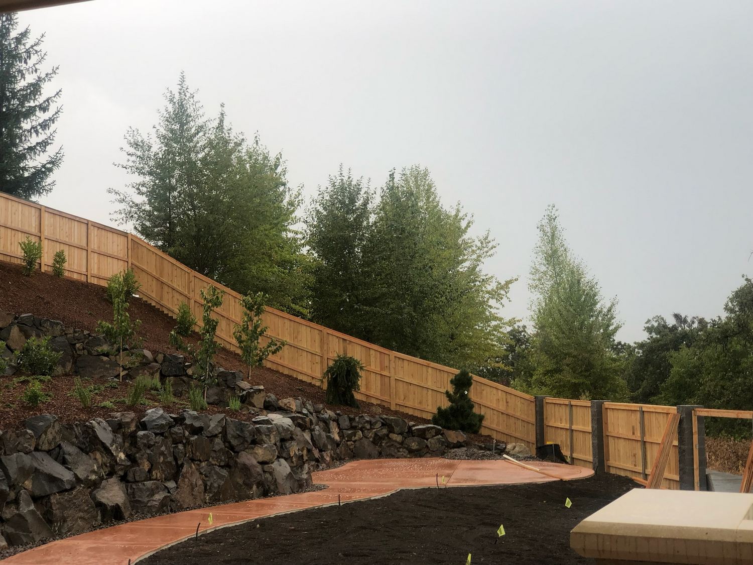 Landscaped slope shaped with rock, planting, and retaining elements