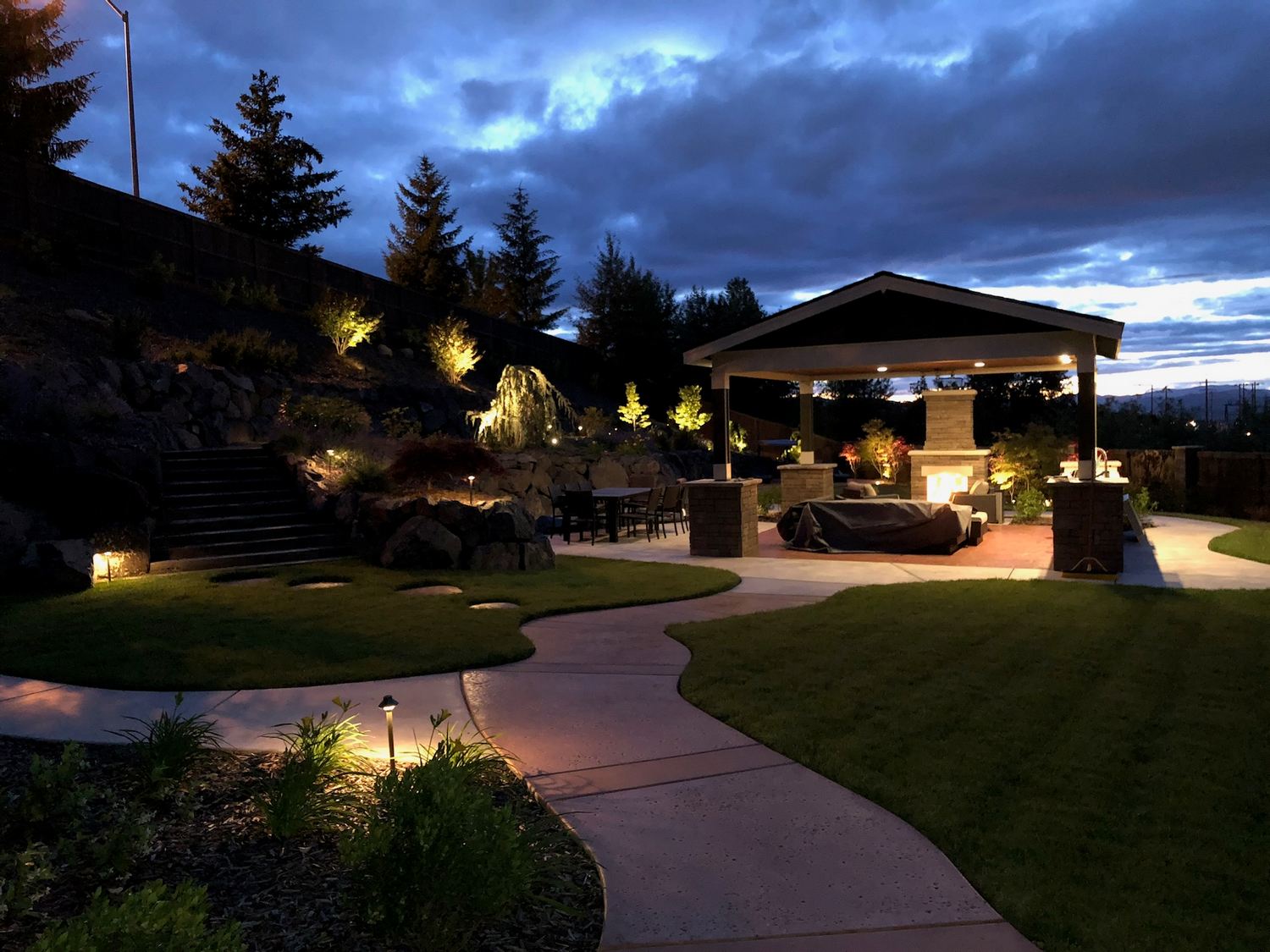 Completed outdoor living area illuminated with landscape lighting at dusk